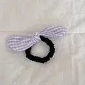 Detalle de cerca de un coletero con lazo de cuadros morados sobre tela blanca suave - Gingham Púrpura