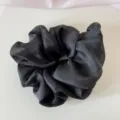 Close-up of elegant black mesh scrunchie with soft ruffled texture and satin sheen - Black