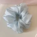 Detailed close-up showing the soft texture of a light blue shimmering mesh scrunchie - Blue