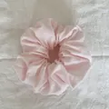 Vue détaillée d'un chouchou rose doux et duveteux sur un tissu blanc texturé - Style de Nuage / Rose Pâle Uni