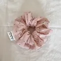 Gros plan détaillé sur un chouchou nuage rose à pois doux sur un tissu blanc texturé - Style de Nuage / Grands Pois Roses