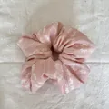 Détail montrant la broderie florale délicate sur le tissu rose du chouchou nuage. - Style de Nuage / Broderie Rose