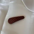 Vue détaillée d'une pince à cheveux en tissu marron à pois blancs sur fond satin - Pince à Cheveux Goutte d'Eau / Pois Café