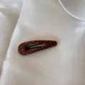 Vue détaillée d'une barrette à pois en tissu marron posée sur de la soie blanche - Pince à Cheveux Goutte d'Eau Ajourée / Pois Café