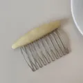 Detail of a yellow fabric hair comb with silver metal teeth on a neutral background. - Yellow Solid Color Comb