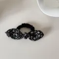 Macro view of a stylish black floral print bow scrunchie on a minimalist white surface - Scrunchie (Black Floral Bow) / Black
