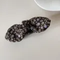 Close-up detail of the vintage floral print on a dark fabric bow hair clip accessory - Banana Clip (Coffee Floral Bow)