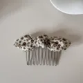 Detailed view of a vintage floral print fabric bow hair comb with metallic teeth accessory. - Hair Comb (Beige Floral Bow)