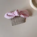 Detailed view of a pink and white checkered bow hair comb on a minimalist beige surface - Pink Plaid Bow Hair Comb