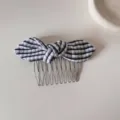 Close-up view of a classic black and white striped bow hair comb with silver metal teeth. - Black Plaid Bow Hair Comb