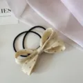 Détail d'un chouchou noeud en tissu à pois beige muni d'un élastique noir haute élasticité. - Jaune