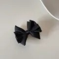 Gros plan d'une élégante pince à cheveux en satin noir multicouche sur fond neutre - Pinces à cheveux bec de canard / L / Noir