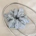 Vue détaillée d'un chouchou bleu clair à pois dans un panier décoratif en maille - Pois bleus