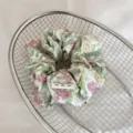 Gros plan d'un chouchou à fleurs avec étiquette placé dans un panier métallique. - Floral Rose Vert