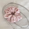 Vue rapprochée d'un chouchou rose à pois posé dans un panier décoratif en métal - Rose à Pois