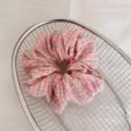 Vue détaillée d'un chouchou à carreaux roses avec texture froncée douce dans un panier en métal - Carreaux Rose et Vert