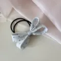 Gros plan d'un chouchou à nœud en tissu bleu clair à pois avec élastiques - Bleu