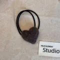 Close-up of a plush brown heart-shaped hair tie on a neutral fabric background - Light Gray Heart Hair Tie