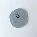 Sottobicchiere minimalista in acrilico grigio con faccina sorridente e forma tonda. - Pietra