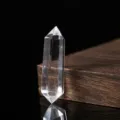 Detaillierte Nahaufnahme einer klaren Quarz-Doppelspitze auf einem dunklen Holz - Bergkristall Doppelspitzstab / 4-5cm