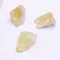 Dettaglio macro di tre pietre di cristallo giallo grezzo irregolari su sfondo bianco - Citrino