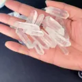 Main tenant des pointes de quartz clair montrant la transparence du cristal - Moyen Pilier de Cristal (Pack de 100)