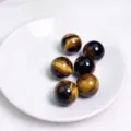 Sfere di cristallo occhio di tigre naturale con venature dorate su piatto bianco - Sfera di Occhio di Tigre