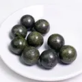 Set di sfere di cristallo verde scuro naturale presentate su un piattino di ceramica - Sfera di Pirite