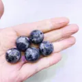 Cinque sfere di cristallo di labradorite naturale con riflessi blu tenute nel palmo della mano - Sfera di Pietra Fiammata