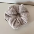 Makro-Detailaufnahme der weichen, flauschigen Strickwolle-Textur dieses beigen Scrunchies - Kaffee Plüsch Haargummi