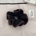 Dettaglio di un elastico per capelli arricciato nero e marrone su panno beige. - Nero con Bordo Caffè / Nero