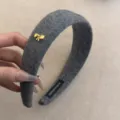 Vista detallada de una diadema acolchada de lana gris con un elegante lazo dorado. - Gris