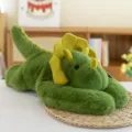 Simpatico peluche di dinosauro triceratopo verde disteso come morbido cuscino per il sonno - 30cm / Dinosauro