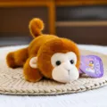 Adorable muñeco de mono de peluche suave en postura tumbada sobre un tapete de paja tejido - Mono / 20cm