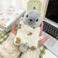 Adorable grey plush seal keychain holding a cute bear pattern pillow backpack charm. - Seal