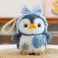 Adorable plush penguin keychain accessory with blue ruffled bow hat and fish detail - Headband Style / 15cm