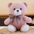 Adorable pink teddy bear plush toy with a decorative bow tie sitting on a woven mat - Ribbon Style / Pink