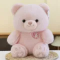 Adorable oso de peluche rosa suave con una linda insignia en forma de corazón en el pecho - Rosa / 25cm