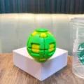 Green and yellow 3D fidget gear ball stress relief toy on a white display pedestal - No Keychain / Green