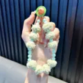 Un adorable llavero de cuentas verde menta con pompones esponjosos en la mano. - Con Junta / Verde