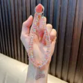Funkelnde rosa Kristall-Handykette mit schimmerndem Fischschwanz-Anhänger als Geschenk. - Rosa