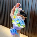 Llavero de muñeca de ganchillo con birrete de graduación y flores azules para bolso - Púrpura