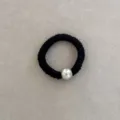 Detail view of a black elastic silk hair scrunchie with a glossy white pearl bead - Black