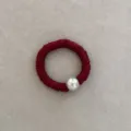 Macro view showing the elegant red silk texture and large pearl detail of hair tie - Red