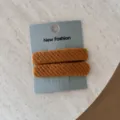 Dettaglio di due mollette per capelli in tessuto twill arancione su base grigia. - Un paio / Arancione