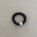 Close-up detail of a premium black silk scrunchie featuring a large silver pearl bead - Gray