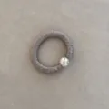 Close-up of elegant taupe silk hair ring with metallic silver ball bead detail - Khaki