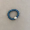 Detail of a blue silk scrunchie featuring a large lustrous pearl charm for hair. - Blue