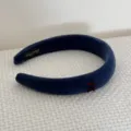Close-up detail of a navy blue velvet padded headband featuring a red bow accent - Deep Blue Bow Headband