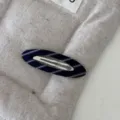 Dettaglio di un fermaglio per capelli in tessuto a righe blu navy su sfondo trapuntato - Fermaglio per Capelli Ovale Vuoto / Saia Blu